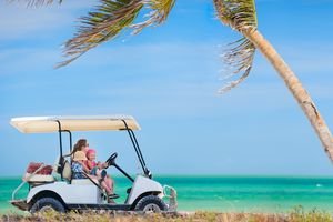 Family driving golf cart along the tropical beach